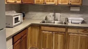 A kitchen with wooden cabinets, a microwave, a sink, and a refrigerator.