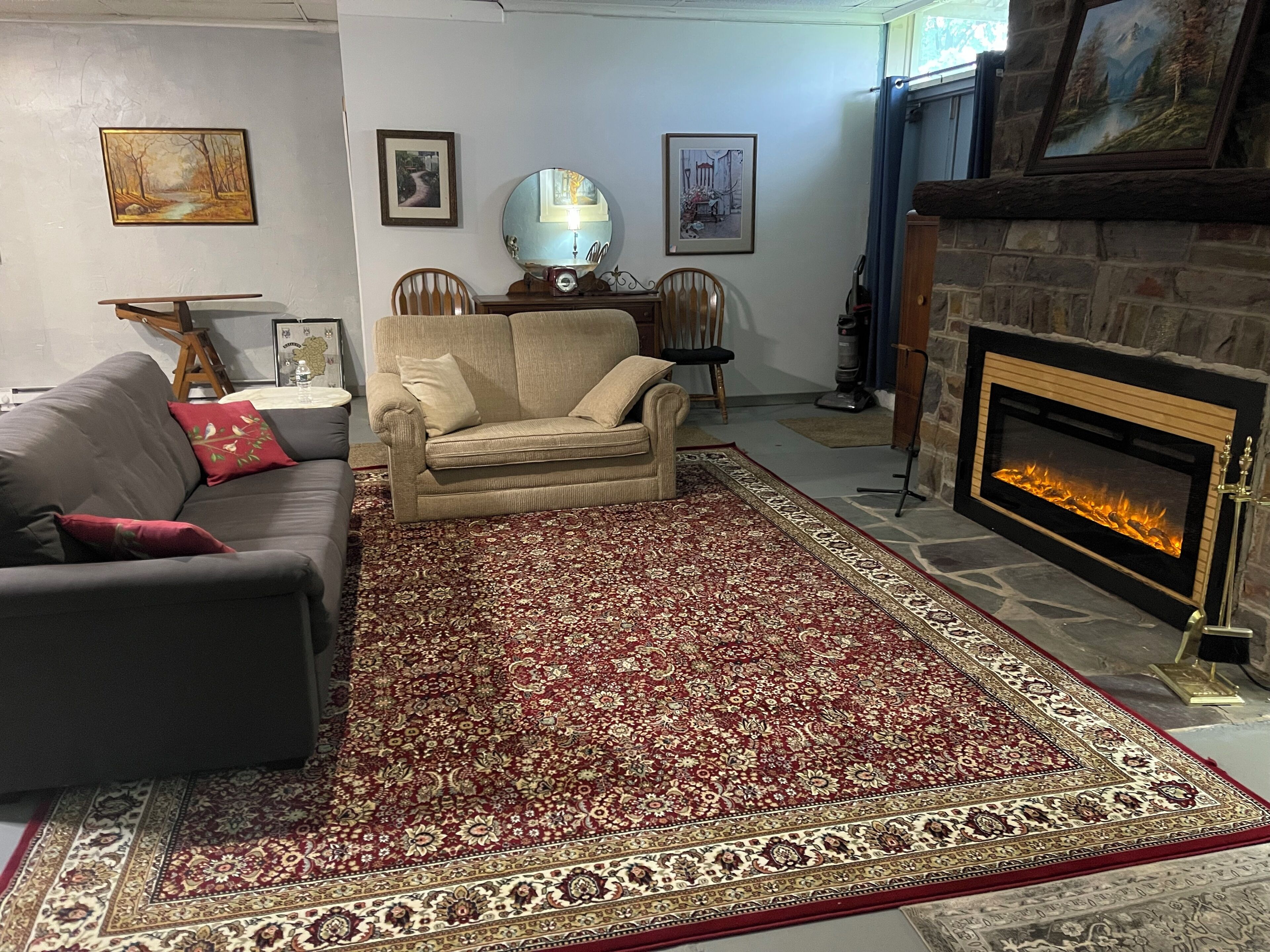 A living room with a fireplace, a sofa, a chair, and a patterned rug.