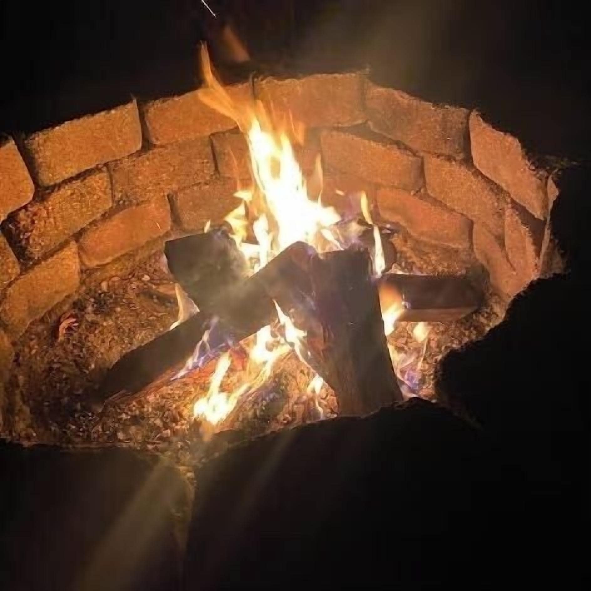 A fire pit with burning logs and flames.