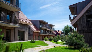 A modern residential building with multiple balconies, a well-maintained lawn, and a clear sky. - New 2025 Pervalka Neringa Flat White Dunes: AC, Heating, Private Balcony (Pervalka)