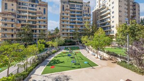Un ensemble immobilier résidentiel comprenant plusieurs balcons, une aire de jeux et un espace vert avec un terrain de football.