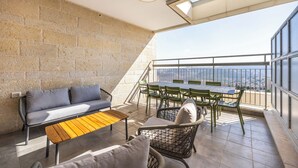 Un balcon avec un canapé, des chaises et une table, d’où l’on a une vue sur le paysage urbain.