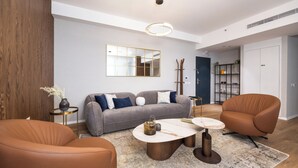 Un salon moderne avec un canapé gris, des fauteuils en cuir marron, une table basse et un grand miroir au mur.