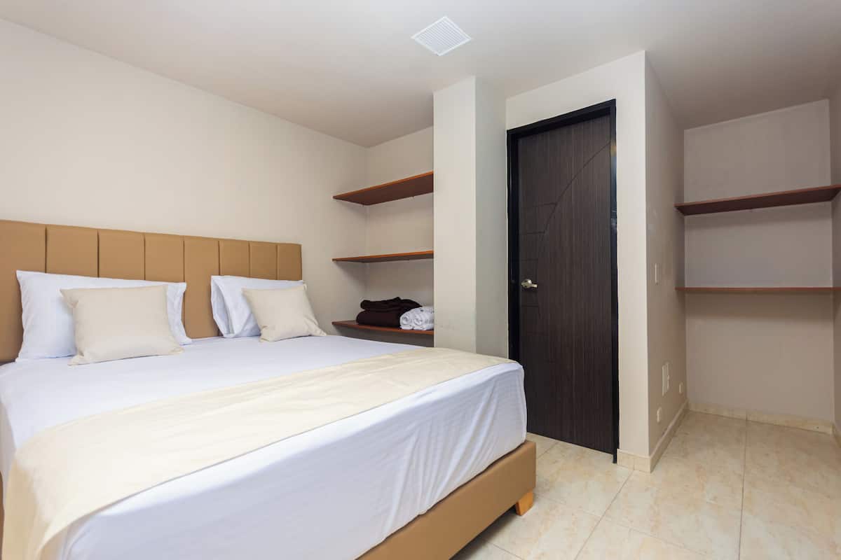 A bedroom with a bed, a wardrobe, and built-in shelves.