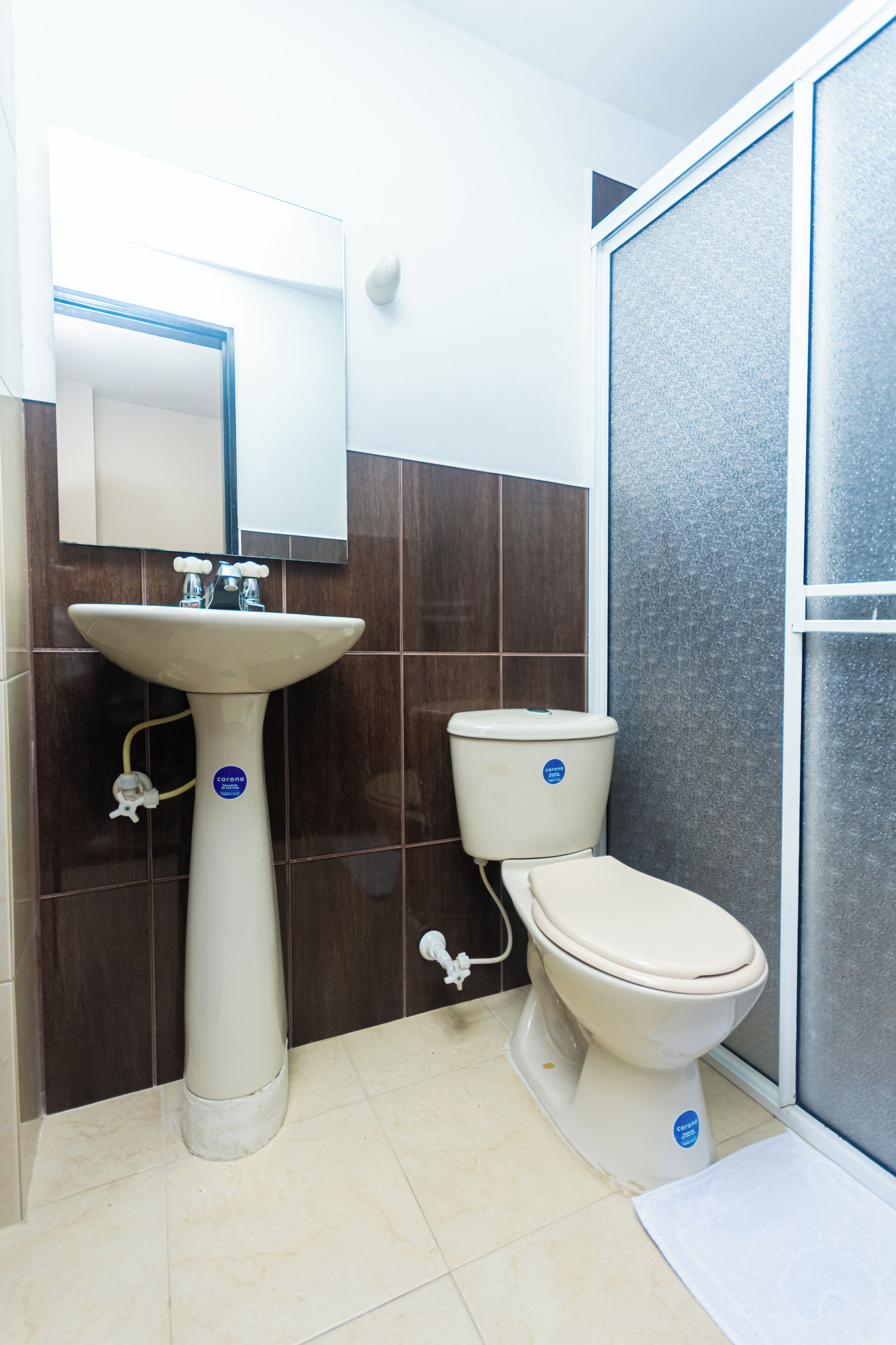 Une salle de bain avec un lavabo sur colonne, des toilettes et un miroir au-dessus du lavabo.
