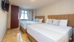 A hotel room with two beds, a TV, a wardrobe, and a window with curtains. - Hotel Bossanova (Rionegro)
