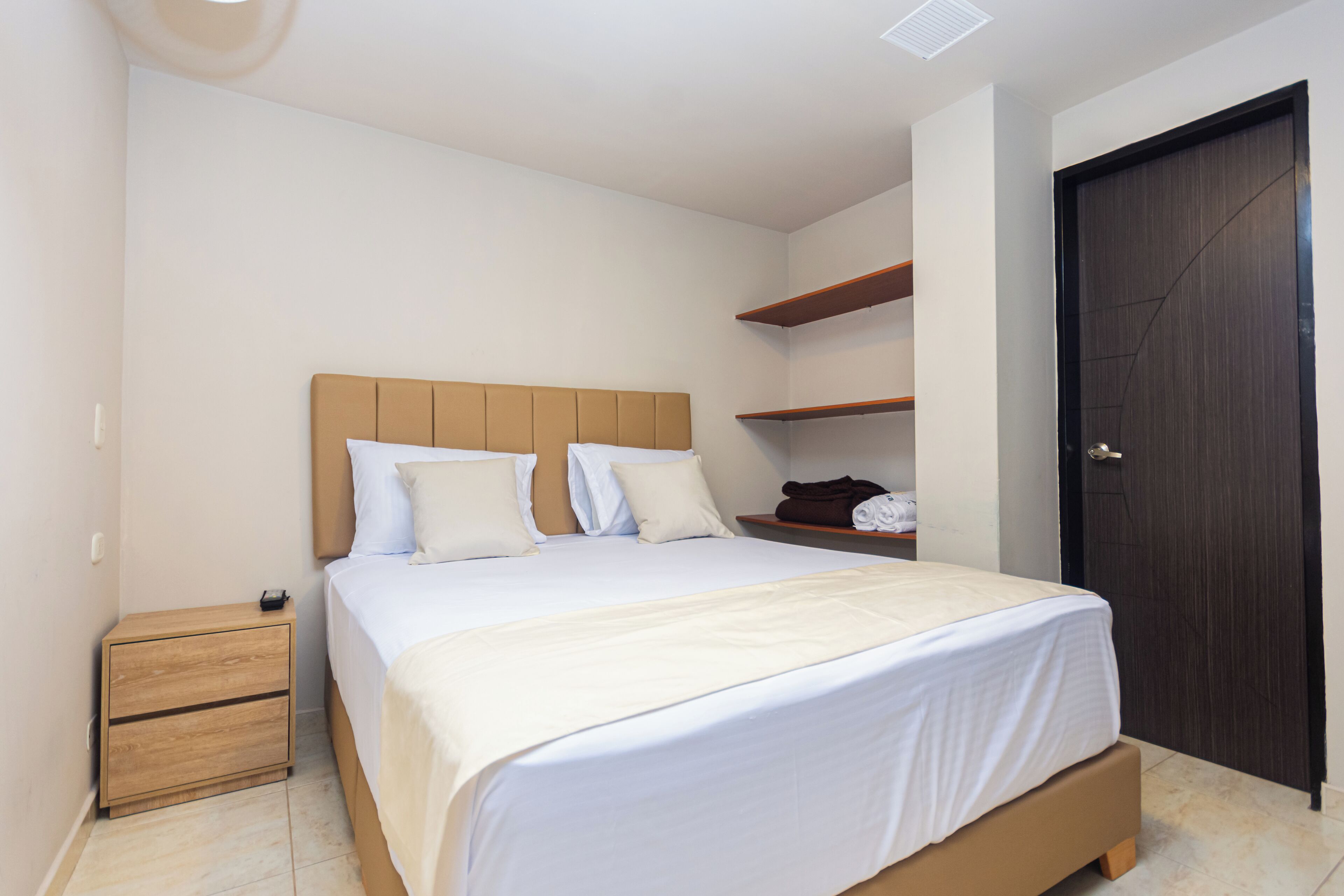 A bedroom with a bed, a nightstand, a wardrobe, and a door.