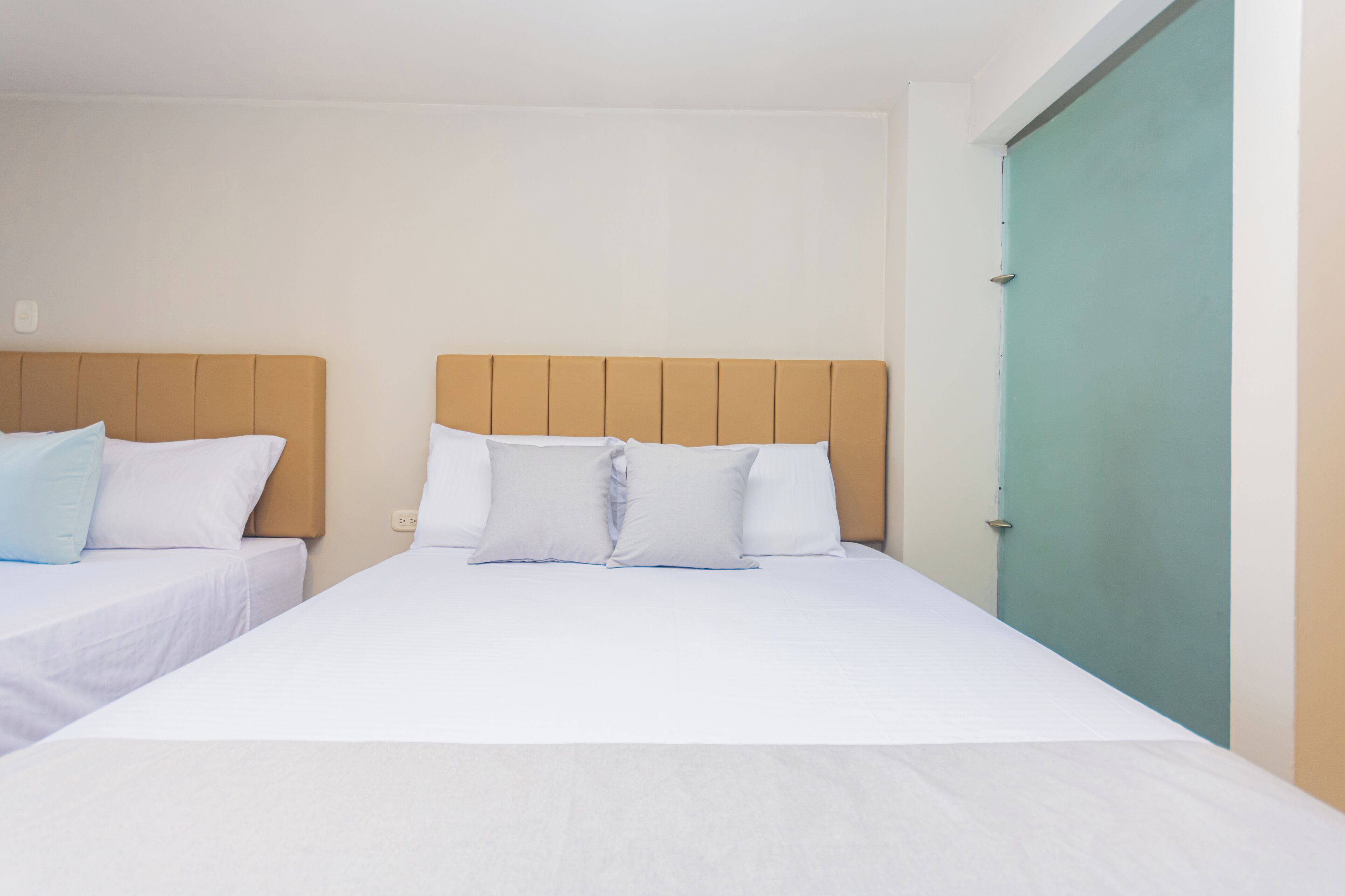 A hotel room with two single beds, each with a wooden headboard and white bedding.