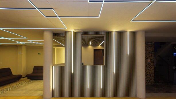 A modern lobby with geometric ceiling lighting, a reception desk, and seating area. - Hotel Bossanova (Rionegro)