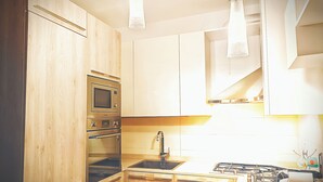 A modern kitchen with wooden cabinets, stainless steel appliances, and pendant lighting.