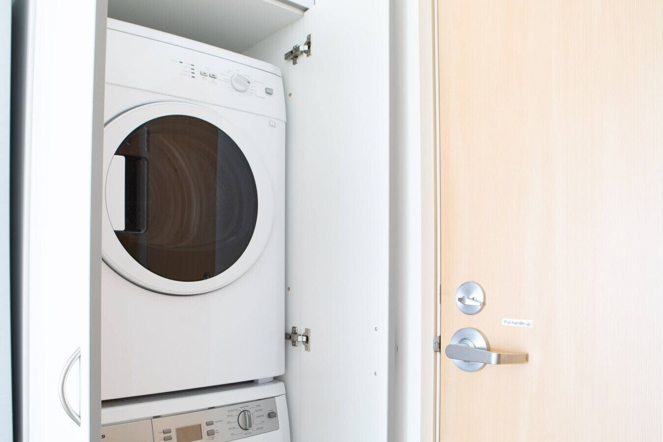 Vue de face d’un lave-linge blanc, avec un panneau de commande, une porte en bois dotée d’une poignée et un verrou en métal.