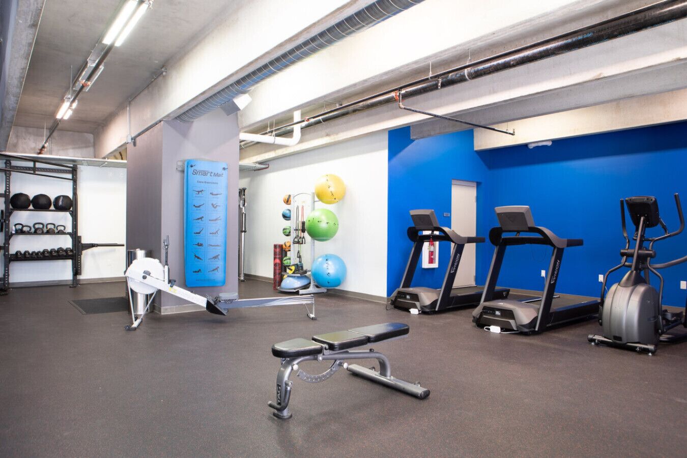 Une salle de sport équipée de matériel d’exercice, de tapis de course et d’un SmartMat.