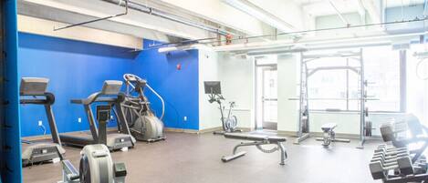 A gym with treadmills, stationary bikes, and weight benches.