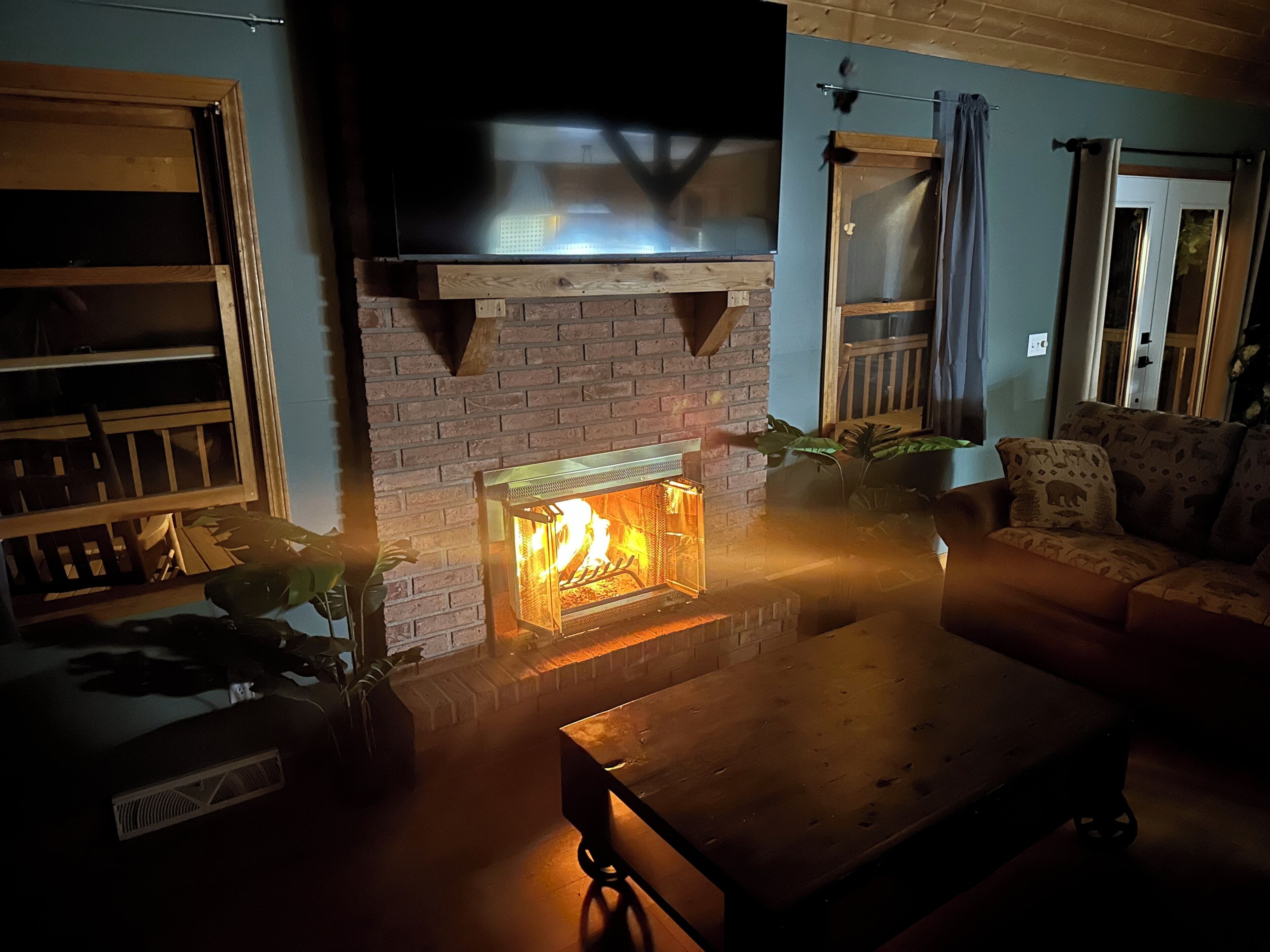 Ein gemütliches Wohnzimmer mit Kamin aus Ziegelsteinen, einem Holztisch und einer bequemen Couch.