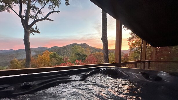 A hot tub with a view of a forested mountain range.