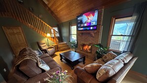 A cozy living room with a fireplace, comfortable seating, and a TV mounted on the wall.