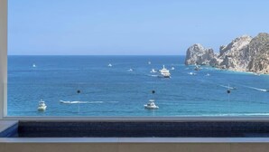 A coastal view with boats on the water and rocky cliffs in the background. - Medano Beach Cabo Resort 3 Bedroom  (Cabo San Lucas)