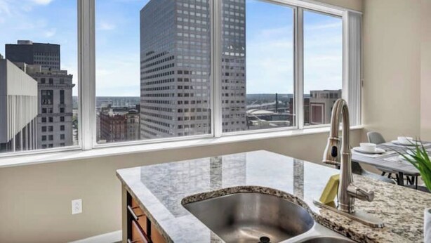 A modern kitchen with a large window, a stainless steel sink, and a granite countertop.