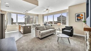 A modern apartment with a kitchen, living area, and large windows offering city views.