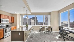 A modern kitchen with a large island, dining area with chairs, and a view of the city.