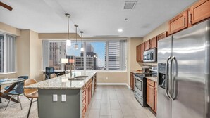A modern kitchen with a large island, stainless steel appliances, and a view of the city skyline.