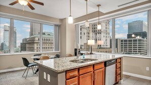 A modern kitchen with a large island, built-in appliances, and large windows offering city views.