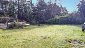 Un espace extérieur verdoyant, doté d’une structure en bois et d’un véhicule.