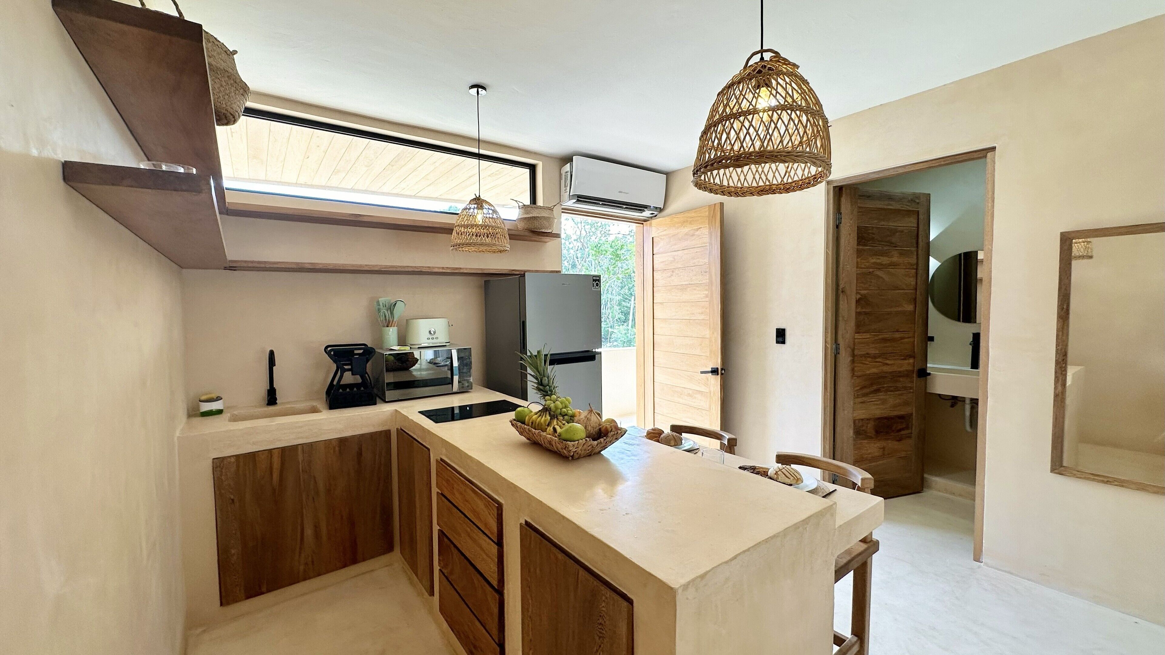 A modern kitchen with a central island, wooden cabinets, a built-in oven, and a hanging light fixture.