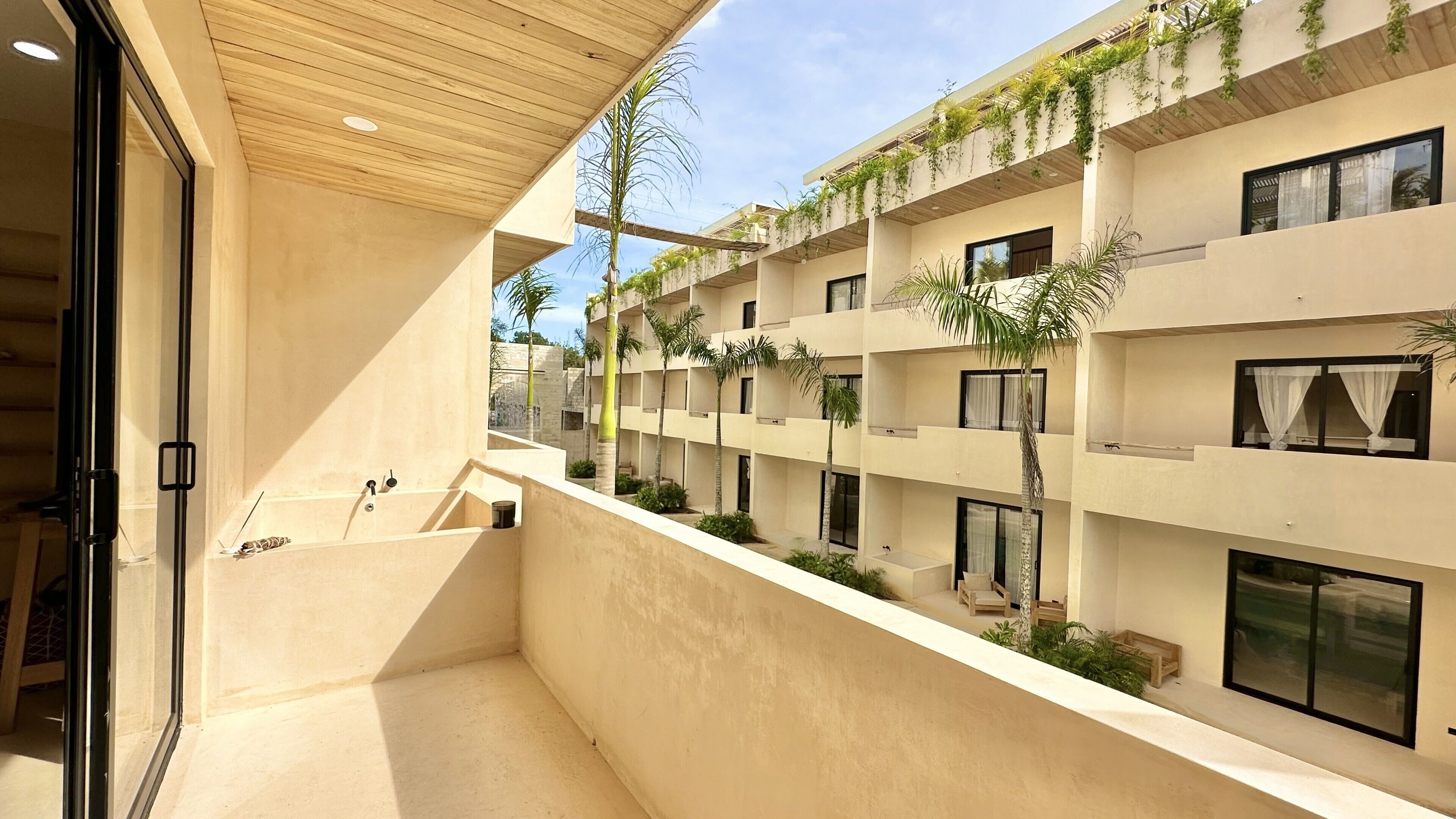 Un bâtiment moderne doté de nombreux balcons, dont certains sont ornés de plantes.