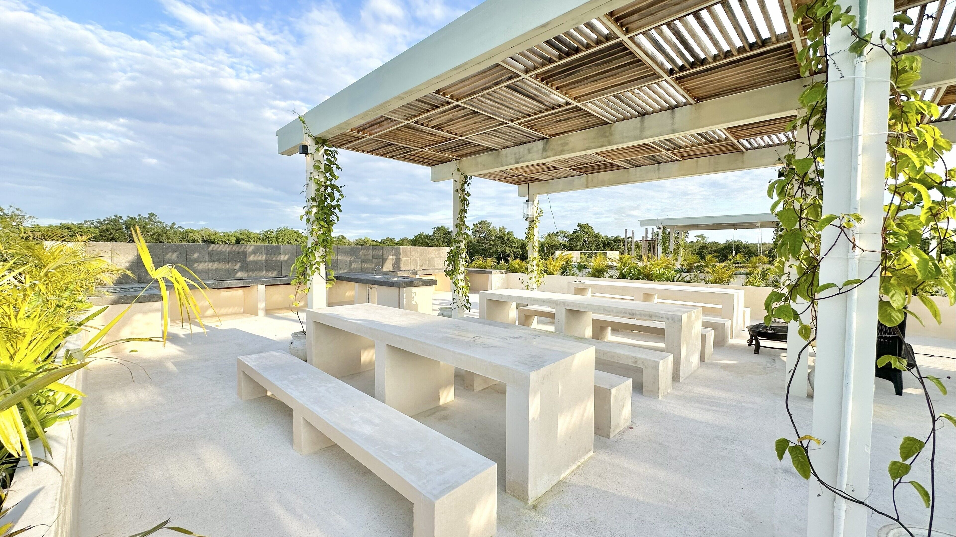 An outdoor seating area with concrete benches and a pergola structure.