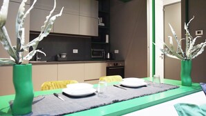 A dining table set with plates, cutlery, and a glass, flanked by two green vases with white plants.