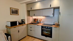 A compact kitchen with a microwave, coffee maker, toaster, and oven.