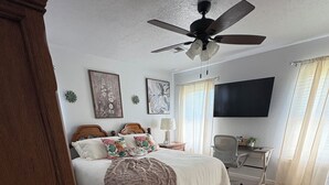 A bedroom with a bed, a ceiling fan, a desk, and a TV. - Jennie May's Retreat offers a comfortable place to rest and recharge! (Enid)