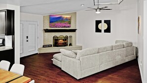 Una sala de estar moderna con chimenea, un sofá y un comedor con mesa y sillas de madera.