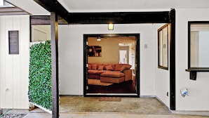 Un pasillo que conduce a una sala de estar con un sofá marrón, un felpudo y una puerta marcada con una 'B'.
