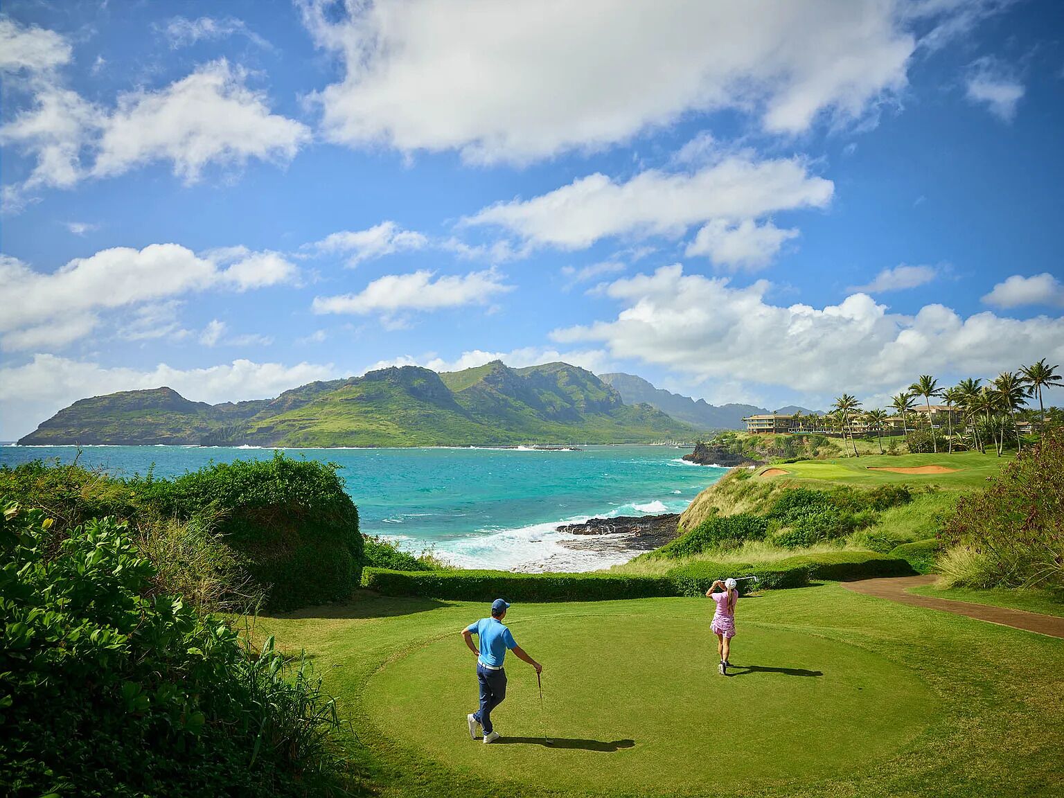 Ein Golfplatz mit Blick auf das Meer und die Berge.