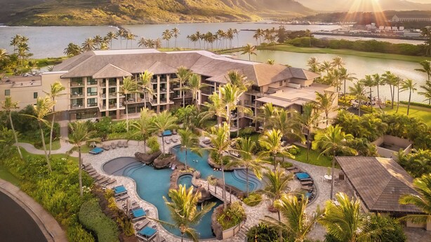A resort with a pool area, palm trees, and a view of the mountains.