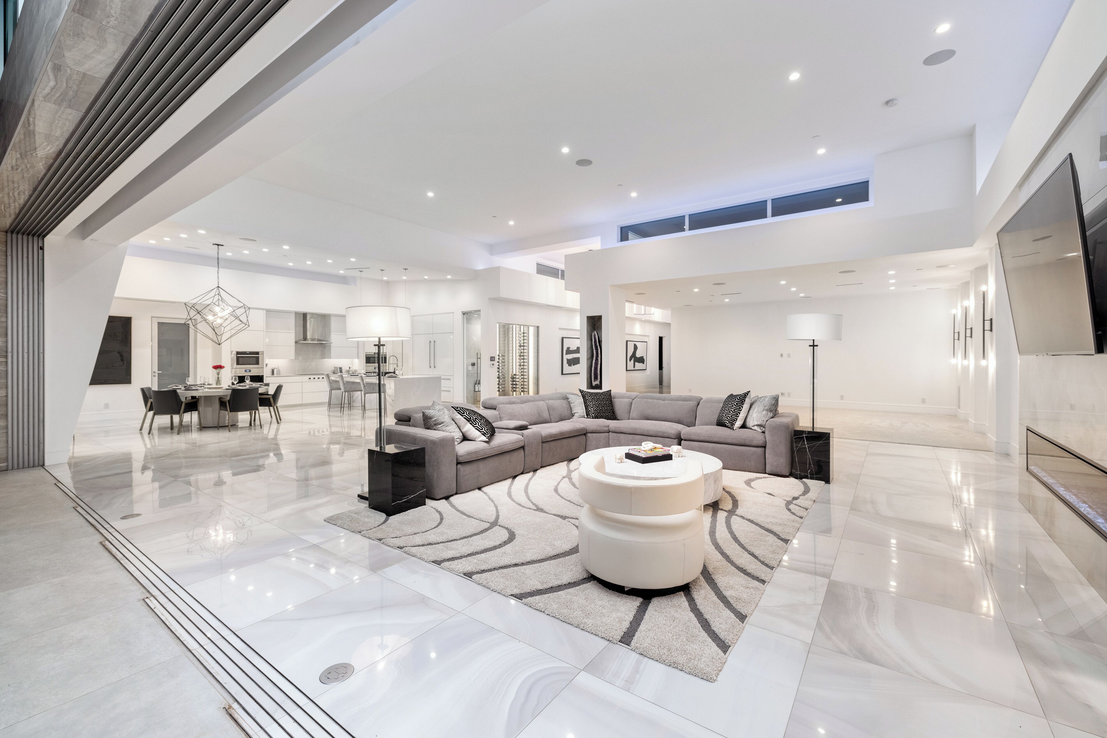 A spacious living area with a large sectional sofa, a round coffee table, and a dining table with chairs.