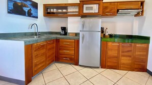 A kitchen with wooden cabinets, a stainless steel refrigerator, a microwave, and a coffee maker. - Ocean view Penthouse (Puerto Ayora, Santa Cruz Island)