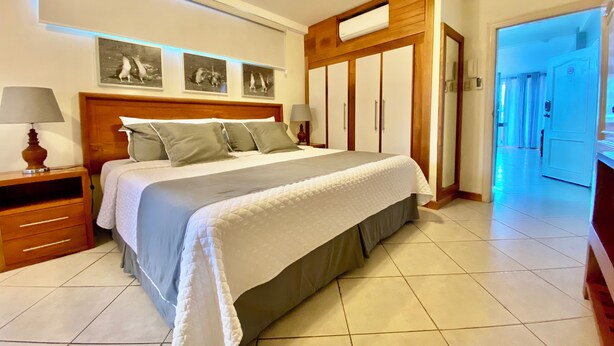 A neatly arranged bedroom with a large bed, bedside tables, a wardrobe, and a ceiling light. - One Bedroom with private balcony (Puerto Ayora, Santa Cruz Island)