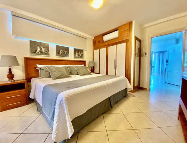 A neatly arranged bedroom with a large bed, bedside tables, a wardrobe, and a ceiling light.