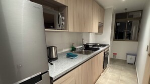 A modern kitchen with stainless steel appliances, wooden cabinets, and a tiled floor. - Spacious and cozy apartment with beautiful view (Valparaíso)