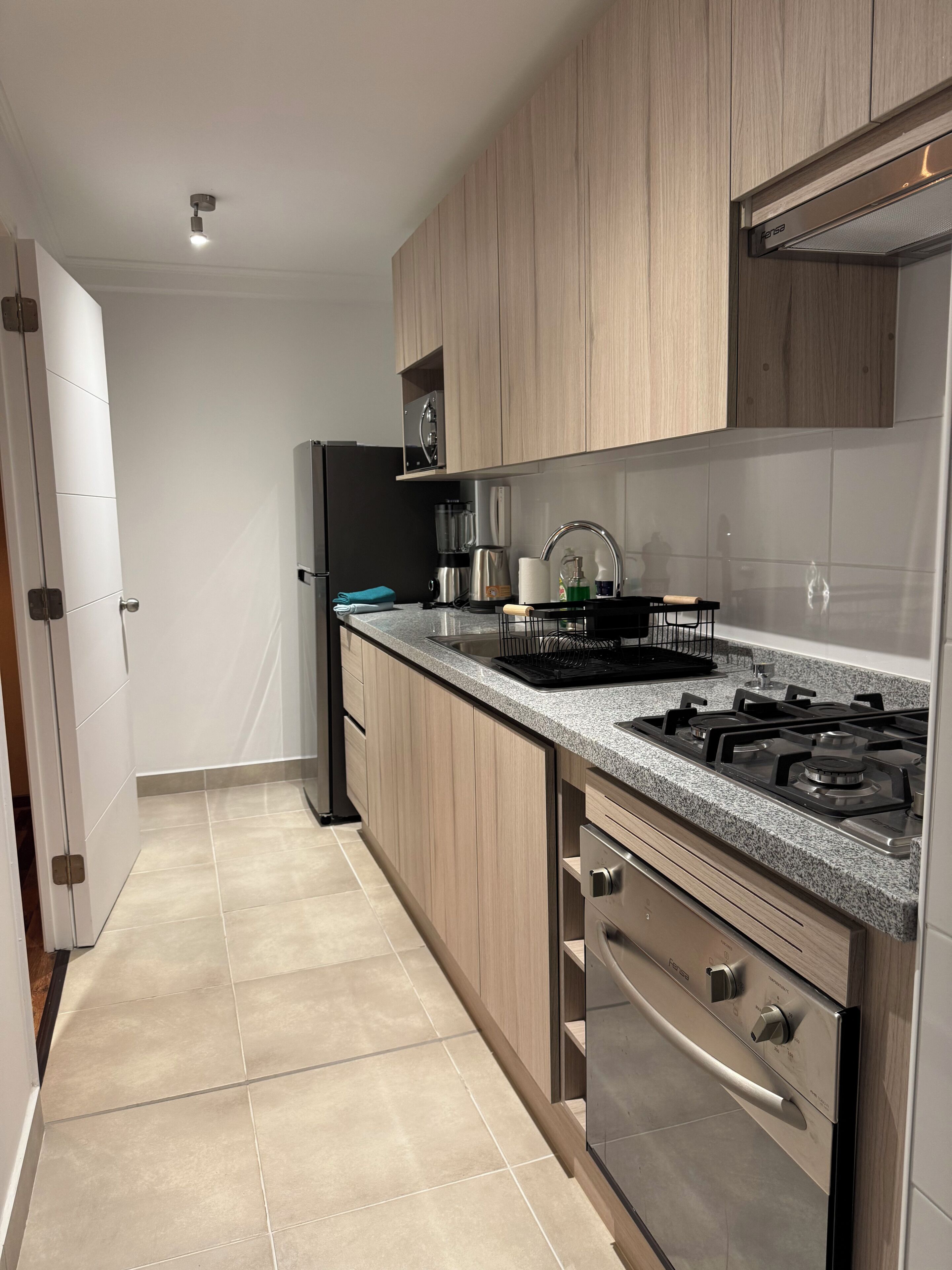 A modern kitchen with wooden cabinets, a stainless steel stove, and a black refrigerator.