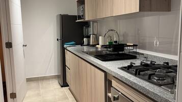 A modern kitchen with wooden cabinets, a stainless steel stove, and a black refrigerator.