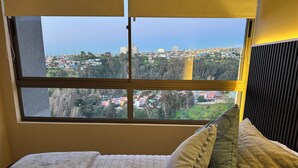 A bed with a view of a cityscape through a window. - Spacious and cozy apartment with beautiful view (Valparaíso)