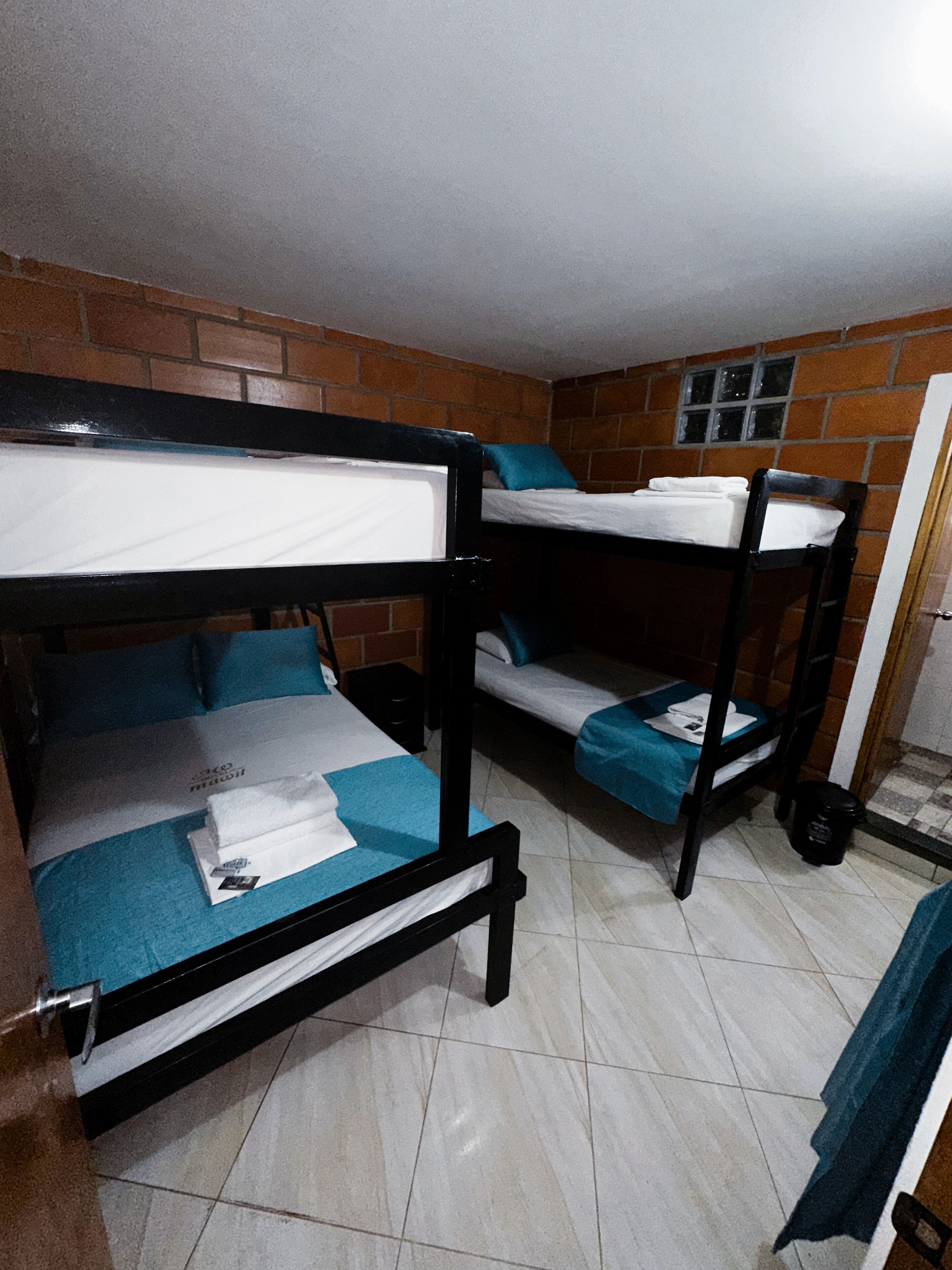 A room with two bunk beds, a tiled floor, and a brick wall.