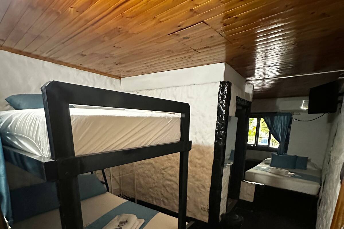 A bunk bed with a blue and white mattress, a small bedside table, and a window with curtains.
