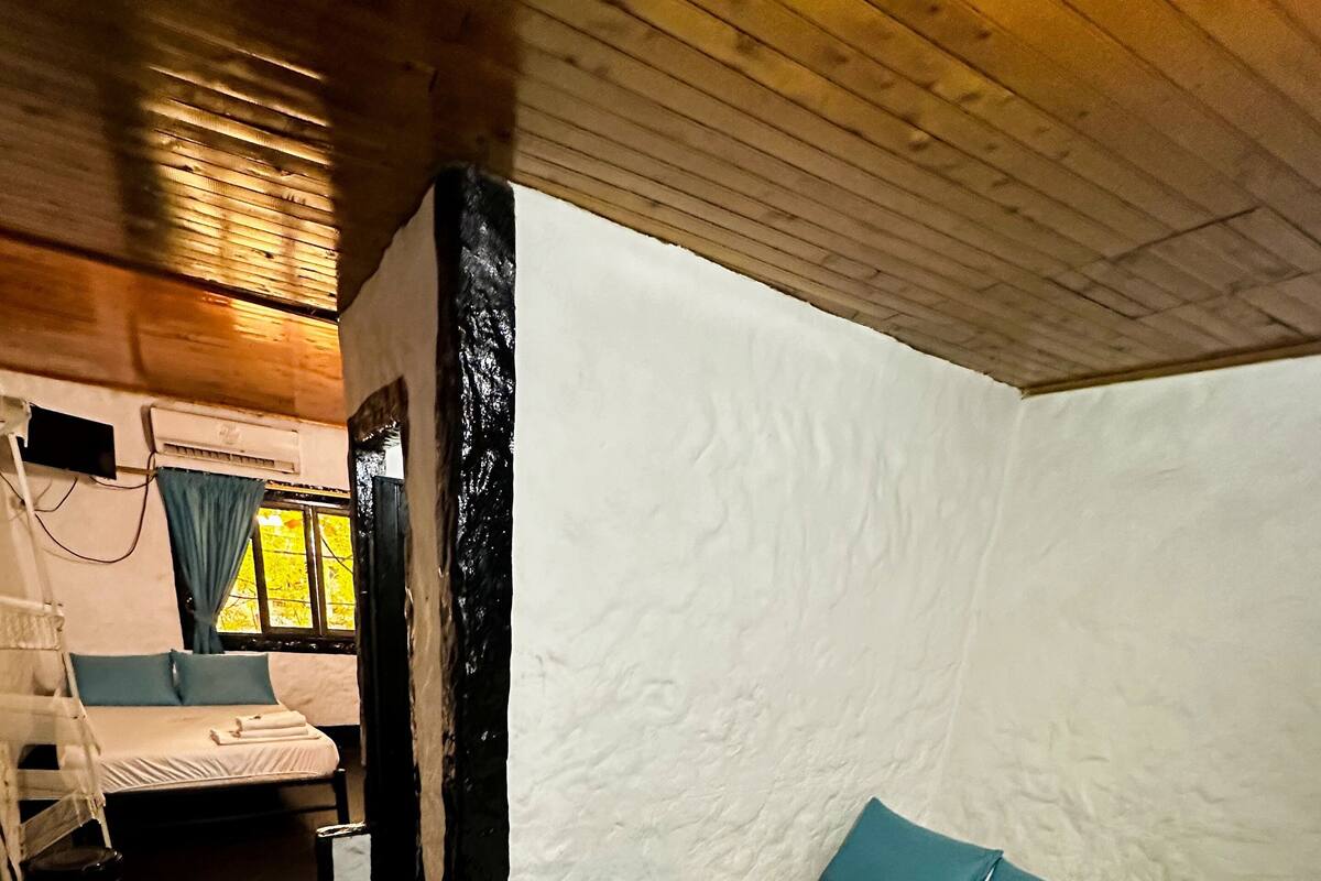 A room with a bed, a small table, and a window with curtains.
