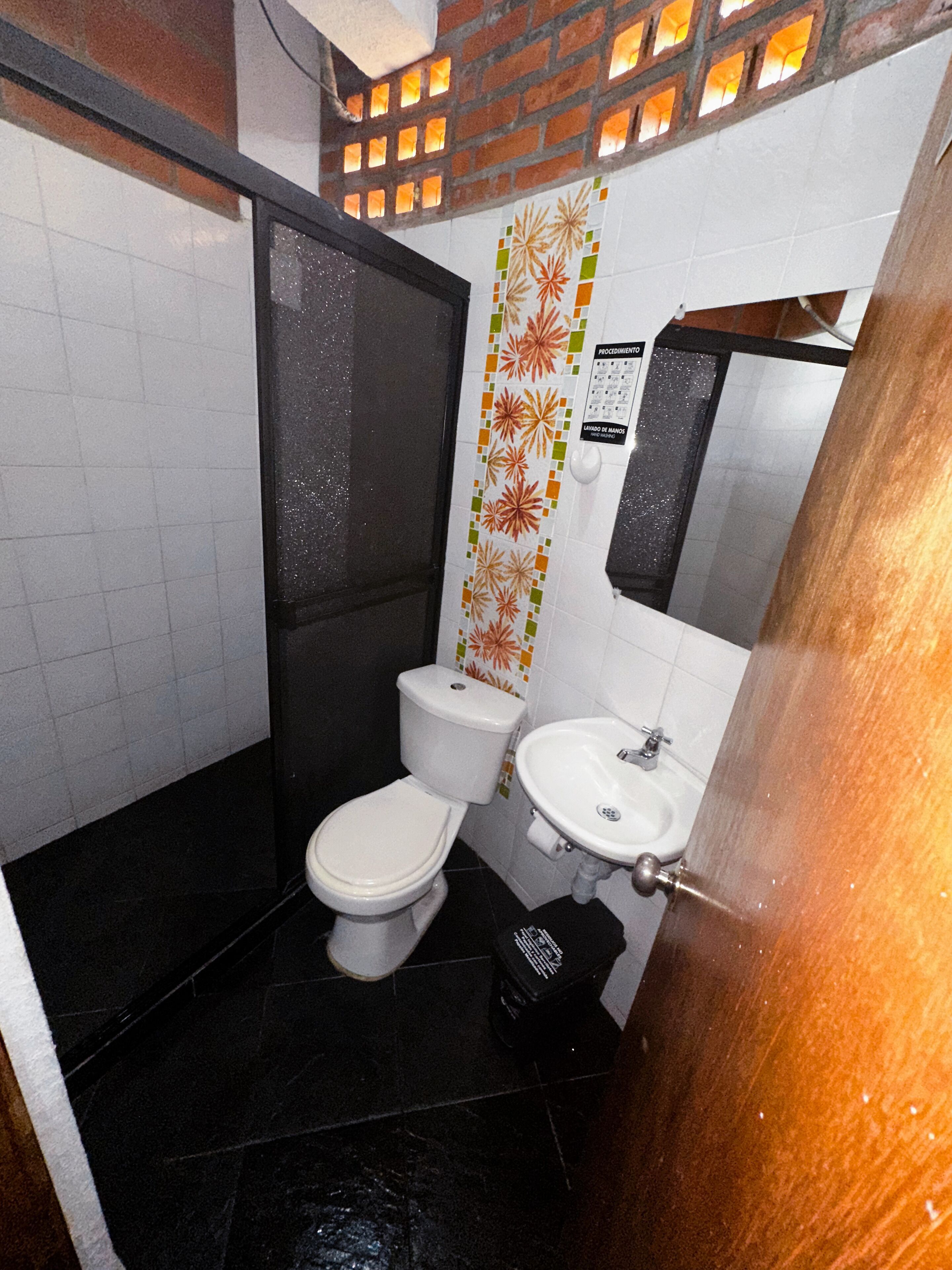 Un baño pequeño con inodoro, lavamanos y ducha.