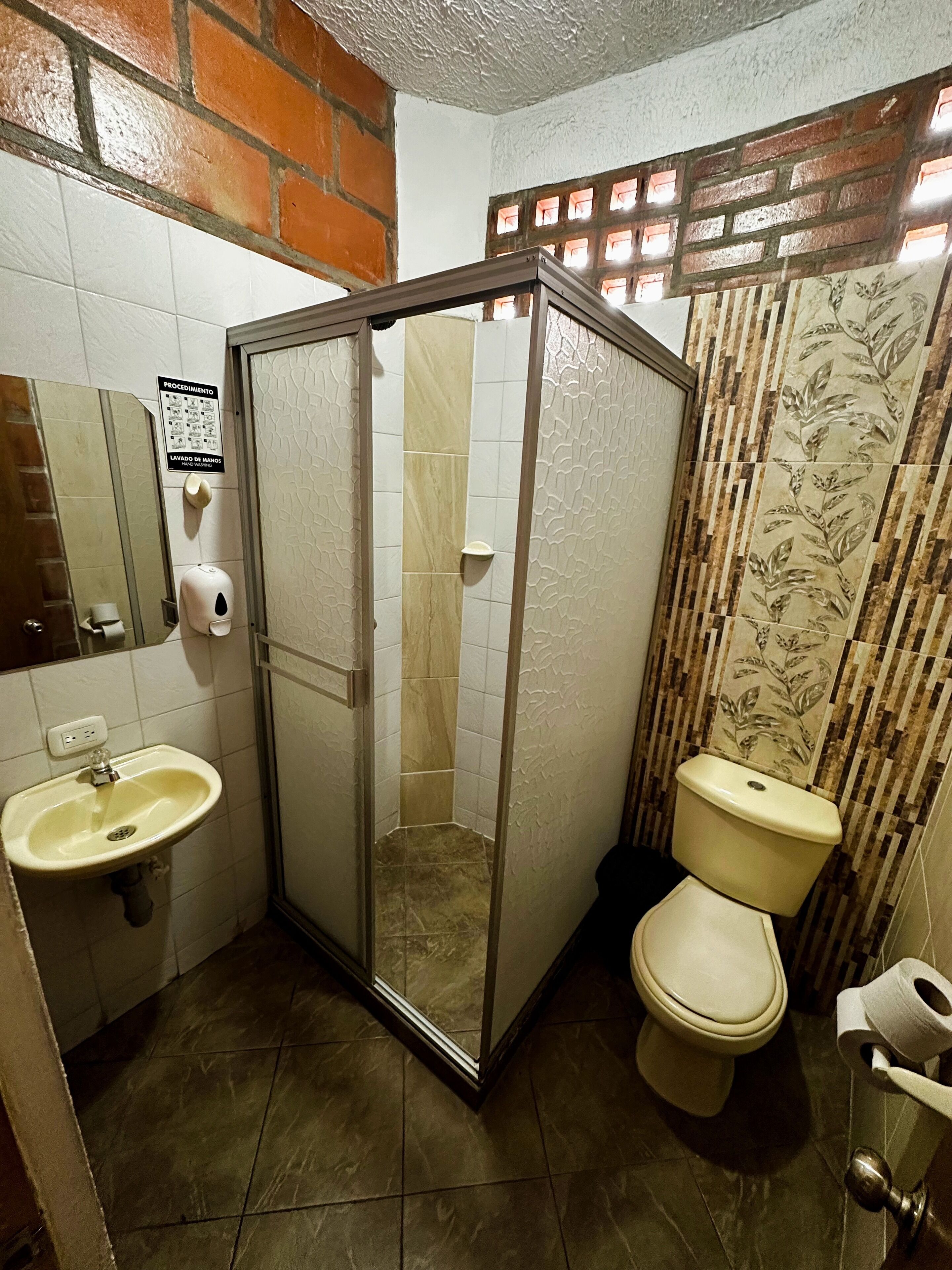 A bathroom with a shower enclosure, toilet, sink, and a mirror.